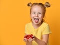 Young baby girl kid hold berries fruits in hands surprised happy laughing screaming on yellow Royalty Free Stock Photo