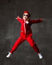 Young baby girl kid jumping in red cloth and sunglasses on dark grey wall Royalty Free Stock Photo