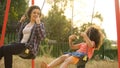 Young babysitter playing with carefree kid, swinging outdoor at child playground Royalty Free Stock Photo