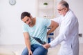 Young back injured man visiting experienced male doctor Royalty Free Stock Photo