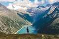 Young backpacker boy with the back at the camera watching a beautiful view over a lake in the Alps, scenic mountains in the Royalty Free Stock Photo