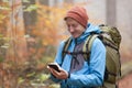 Young backpacker looking at smartpone in a colorful forest in autumn