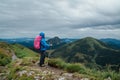 Young backpacker woman dressed blue rain suit with tracking poles with backpack enjoying Slovakian Mala Fatra mountain range. Royalty Free Stock Photo