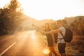 Young backpacking adventurous couple hitchhiking on the road.Stopping transportation.Travel lifestyle.Low budget traveling Royalty Free Stock Photo