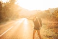 Young backpacking adventurous woman hitchhiking on the road. Stopping a car with a thumb. Travel lifestyle. Low budget traveling Royalty Free Stock Photo