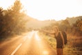 Young backpacking adventurous woman hitchhiking on the road.Stopping a car with a thumb.Travel lifestyle.Low budget traveling Royalty Free Stock Photo