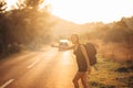 Young backpacking adventurous woman hitchhiking on the road. Stopping a car with a thumb. Travel lifestyle. Low budget traveling Royalty Free Stock Photo