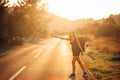 Young backpacking adventurous woman hitchhiking on the road.Stopping a car with a thumb.Travel lifestyle.Low budget traveling Royalty Free Stock Photo