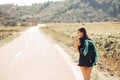 Young backpacking adventurous woman hitchhiking on the road.Traveling backpacks volume,packing essentials.Travel lifestyle Royalty Free Stock Photo