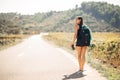 Young backpacking adventurous woman hitchhiking on the road.Traveling backpacks volume,packing essentials.Travel lifestyle Royalty Free Stock Photo