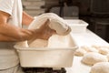 Young baker in bakery shop sprinkling flour with strainer on fresh bread dough in front of oven. concept of traditional manual Royalty Free Stock Photo