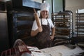 Young baker with chef cap preparing pastries in bakery.