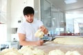 A young Baker puts a portion of dough on the table. The process of making tortillas. Hands and dough are out of focus. Yeast dough