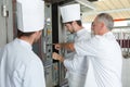 Young bakers putting unbaked bread in hot-oven in bakery