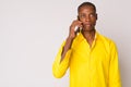 Young bald African businessman thinking while talking on the phone Royalty Free Stock Photo