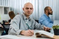 Young bald business man sitting at desk in office, working on computer Royalty Free Stock Photo