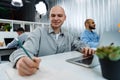 Young bald business man sitting at desk in office, working on computer Royalty Free Stock Photo