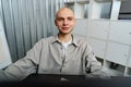 Young bald business man sitting at desk in office, working on computer Royalty Free Stock Photo