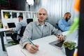 Young bald business man sitting at desk in office, working on computer Royalty Free Stock Photo