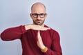 Young bald man with beard standing over white background wearing glasses doing time out gesture with hands, frustrated and serious Royalty Free Stock Photo