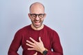 Young bald man with beard standing over white background wearing glasses smiling and laughing hard out loud because funny crazy Royalty Free Stock Photo
