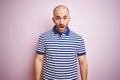 Young bald man with beard wearing casual striped blue t-shirt over pink isolated background afraid and shocked with surprise Royalty Free Stock Photo