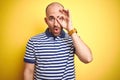 Young bald man with beard wearing casual striped blue t-shirt over yellow isolated background doing ok gesture shocked with Royalty Free Stock Photo