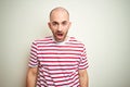 Young bald man with beard wearing casual striped red t-shirt over white isolated background afraid and shocked with surprise and Royalty Free Stock Photo