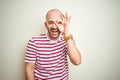 Young bald man with beard wearing casual striped red t-shirt over white isolated background doing ok gesture shocked with Royalty Free Stock Photo