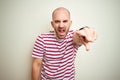 Young bald man with beard wearing casual striped red t-shirt over white isolated background pointing displeased and frustrated to Royalty Free Stock Photo