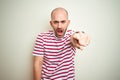 Young bald man with beard wearing casual striped red t-shirt over white isolated background pointing displeased and frustrated to Royalty Free Stock Photo