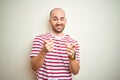 Young bald man with beard wearing casual striped red t-shirt over white isolated background pointing fingers to camera with happy Royalty Free Stock Photo