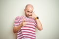 Young bald man with beard wearing casual striped red t-shirt over white isolated background smiling doing talking on the telephone Royalty Free Stock Photo