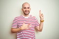 Young bald man with beard wearing casual striped red t-shirt over white isolated background smiling swearing with hand on chest Royalty Free Stock Photo