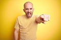 Young bald man with beard wearing casual striped t-shirt over yellow isolated background pointing displeased and frustrated to the Royalty Free Stock Photo