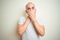 Young bald man with beard wearing casual white t-shirt over isolated background shocked covering mouth with hands for mistake Royalty Free Stock Photo