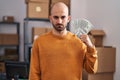 Young bald man with beard working at small business ecommerce holding money thinking attitude and sober expression looking self Royalty Free Stock Photo