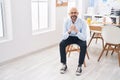 Young bald man business worker smiling confident sitting on chair at office Royalty Free Stock Photo