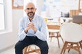 Young bald man business worker smiling confident sitting on chair at office Royalty Free Stock Photo