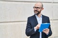 Young bald man business worker smiling confident using touchpad at street Royalty Free Stock Photo