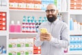 Young bald man customer smiling confident using smartphone at pharmacy