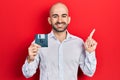 Young bald man holding floppy disk smiling happy pointing with hand and finger to the side Royalty Free Stock Photo