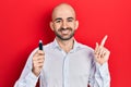 Young bald man holding removable memory usb smiling happy pointing with hand and finger to the side Royalty Free Stock Photo