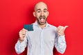 Young bald man holding ssd memory pointing thumb up to the side smiling happy with open mouth Royalty Free Stock Photo