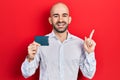 Young bald man holding ssd memory smiling happy pointing with hand and finger to the side Royalty Free Stock Photo