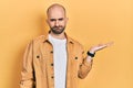 Young bald man presenting with open palms, holding something depressed and worry for distress, crying angry and afraid Royalty Free Stock Photo