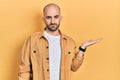 Young bald man presenting with open palms, holding something relaxed with serious expression on face Royalty Free Stock Photo