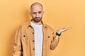 Young bald man presenting with open palms, holding something skeptic and nervous, frowning upset because of problem Royalty Free Stock Photo