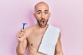 Young bald man shirtless holding razor scared and amazed with open mouth for surprise, disbelief face Royalty Free Stock Photo
