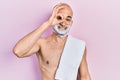 Young bald man shirtless shaving beard with foam smiling happy doing ok sign with hand on eye looking through fingers